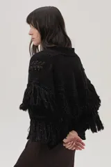 Cárdigan de tejido de punto negro con lurex de colores, detalles calados, trenzas tejidas y flecos en mangas y espalda.