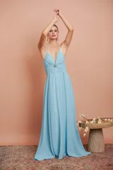 Vestido largo de gasa color celeste, con escote en V profundo y tirantes finos. Presenta una falda larga con gran caída y movimiento.