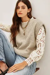 Chaleco de punto color beige, con cuello redondo y volados.