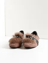 Mocasines de gamuza sintética color marrón, con detalle de pelo sintético en la parte superior y una tira de cuero sintético negro con hebilla metálica. Poseen un diseño de punta redondeada y taco bajo.