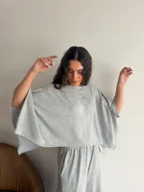 Conjunto de dos piezas de lanilla en color gris melange, compuesto por una blusa de corte amplio con mangas murciélago y escote bote, y un pantalón recto con bolsillos laterales.