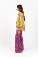 Camisa de manga larga con cuello clásico y cierre frontal de botones, confeccionada en tejido de color verde lima con estampa floral en tonos morados y naranjas.