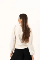 Blusa de cuello redondo con mangas largas tipo globo y puños elásticos. Presenta un diseño de textura combinada en el frente y las mangas.