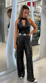 Mono largo negro con estampado sutil, escote halter con cuello alto y abertura en el pecho. Piernas anchas y corte holgado.