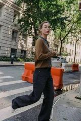 Jersey de punto con cuello polo y cierre frontal de botones. Presenta un diseño de estampado de rombos en el frente en tonos gris y blanco sobre una base color marrón.