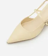 Zapato de tacón color crema, con punta fina, tira delantera y tira trasera con hebilla.