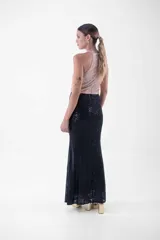 Vestido largo con cuello halter enteramente cubierto de lentejuelas, que combina un cuerpo superior en tono rosado y una falda larga en color negro.