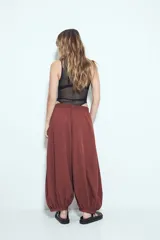 Pantalón ancho estilo Aladdin de tiro bajo, color marrón rojizo, con cintura elastizada y puños ajustados en los tobillos.