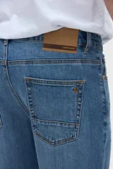 Jean de corte holgado en caderas y cintura, con piernas de calce recto y tiro medio, color azul medio.