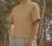 Remera de punto color verde claro, con cuello alto y mangas cortas con terminación ondulada.