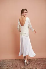 Blusa blanca con bordado de mostacillas y lentejuelas, escote redondo y manga larga.