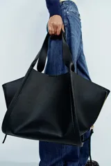 Bolso de hombro maxi shopper negro, con detalle de cremalleras en los laterales, doble asa de hombro y cierre con botón imantado.