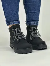 Borcego negro de caña baja con suela track y cordones combinados en blanco y negro.