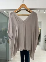 Blusa color beige con escote en V, mangas cortas amplias y diseño holgado con caída fluida.
