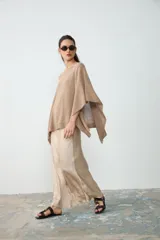 Poncho tejido de punto color tostado, con escote redondo y diseño amplio y asimétrico.