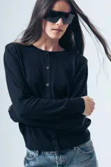 Cardigan negro de punto fino, con cuello redondo, cierre frontal de botones y mangas largas con puños ajustados.
