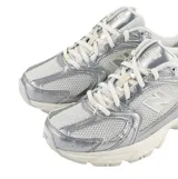 Championes urbanos New Balance modelo 530, con diseño inspirado en el running clásico. Presentan una combinación de malla blanca y revestimientos sintéticos en color plateado metálico, con el logo N característico en los laterales y entresuela con tecnología ABZORB para mayor amortiguación.