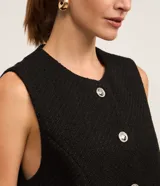 Chaleco blanco de tweed con cuello redondo, abotonado en el frente y corte entallado.