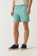 Short de baño liso para hombre, con cintura elástica y cordón ajustable. Cuenta con dos bolsillos laterales, un bolsillo trasero y logo bordado en la parte inferior.