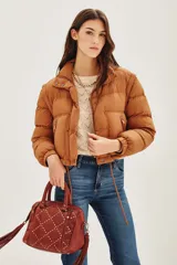 Campera puffer color tostado, con cierre frontal y botones a presión, cuello alto y puños tejidos acanalados.