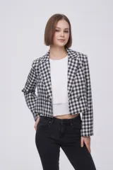 Blazer corto de poliéster con diseño a cuadros en blanco y negro, cuello solapa y cierre frontal de doble botonadura.