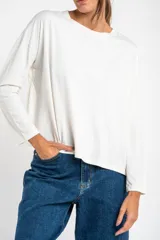 Remera de manga larga color blanco roto, con corte oversize y cuello redondo.