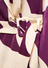 Mono largo de poliéster con estampado abstracto en tonos morado y blanco. Diseño cruzado con cuello pico y solapa, manga larga abotonada, cinturón desmontable y forro interior.