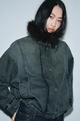 Chaqueta tipo bomber de denim lavado azul, corte holgado, con cuello solapa y aplicación de pelo sintético marrón desmontable. Presenta bolsillos delanteros y bajo acabado en elástico.