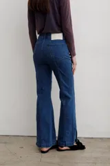 Jean de denim azul de tiro medio, con corte flare y costuras frontales destacadas.