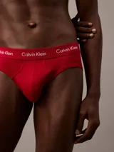 Pack de tres slips Calvin Klein de corte clásico, confeccionados en mezcla de algodón y elastano. Presentan cintura elástica con el logo de la marca y acabado que absorbe la humedad. El set incluye un slip negro, uno gris y uno rojo.