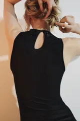 Top negro sin mangas, con cuello redondo y abertura con botón en la espalda. Presenta un detalle de abalorios a tono en el borde del cuello y sisas.