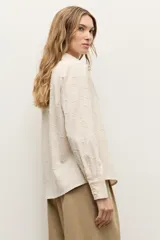 Camisa de manga larga color beige con diseño texturizado en tono sobre tono, cuello clásico y cierre frontal con botones.