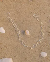 Tobillera plateada con eslabones de diferentes formas y tamaños.