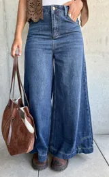 Jean de corte ancho y tiro medio, confeccionado en denim azul oscuro sin lycra. Presenta un diseño de pierna recta y holgada con costuras reforzadas.