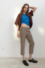 Camisa de cuello solapa y manga corta con dobladillo. Presenta un diseño de corte holgado con bajo asimétrico y aberturas laterales. Cierre frontal mediante botones ocultos bajo una tapeta.