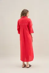 Vestido largo lila de lino, con cuello camisero, mangas cortas, bolsillos frontales con costuras a contratono y aberturas laterales.