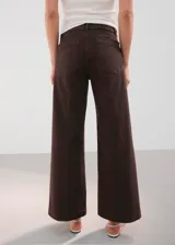 Pantalón de jean marrón de corte wide leg, tiro medio, con bolsillos delanteros aplicados y costuras frontales marcadas.