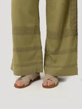 Pantalón de lino orgánico y viscosa color crema, de tiro alto y corte recto, con pinzas delanteras, bolsillos laterales y detalle de trabilla ajustable con hebilla metálica en la cintura.