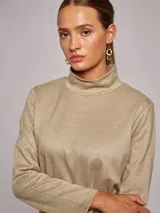 Vestido corto de jersey en color beige, con cuello subido y manga larga. Presenta un corte recto y minimalista.