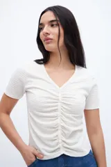 Remera negra con escote en V, cartera de botones, frunces y mangas cortas.