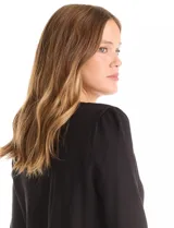 Buzo de punto liviano color blanco, con cuello redondo y mangas largas con frunce en los hombros. Presenta apliques de strass en forma de estrellas o destellos en el frente y puños y cintura acanalados.
