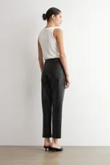 Pantalón de corte recto confeccionado en cuero sintético negro, con tiro medio, cierre frontal con botón y bolsillos laterales.