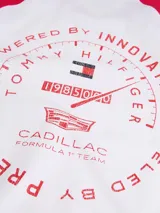 Remera de cuello redondo con diseño de mangas raglán en color rojo y cuerpo en color blanco. Presenta un estampado gráfico en el pecho con banderas de carreras y el logo de la colaboración Tommy Hilfiger x Cadillac Formula 1 Team.