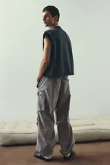 Pantalón cargo de algodón color gris claro, con corte holgado y cintura elástica ajustable con cordón. Presenta bolsillos cargo grandes en las piernas, pliegues cosidos en las rodillas y cordones ajustables en los bajos.