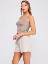 Top crop de punto elastizado color beige, con escote recto y tirantes finos regulables. Presenta una trama texturada con franjas horizontales.