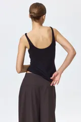 Musculosa en punto acanalado negro, de corte entallado con escote en U pronunciado tanto en el frente como en la espalda.