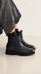 Botas de cuero negro con punta cuadrada, diseño minimalista y suela plana con plataforma baja.