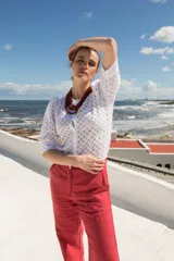 Camisa de estilo romántico confeccionada en tela broderie blanca, con mangas al codo abullonadas y cierre frontal con botones.