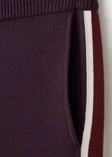 Pantalón de jogging bordó de corte recto y holgado, con bandas laterales en contraste color blanco y bordó. Cuenta con bolsillos laterales y cintura elástica.