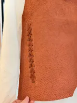 Chaleco artesanal confeccionado en cuero, con diseño de cordones decorativos en el frente y terminaciones rústicas.